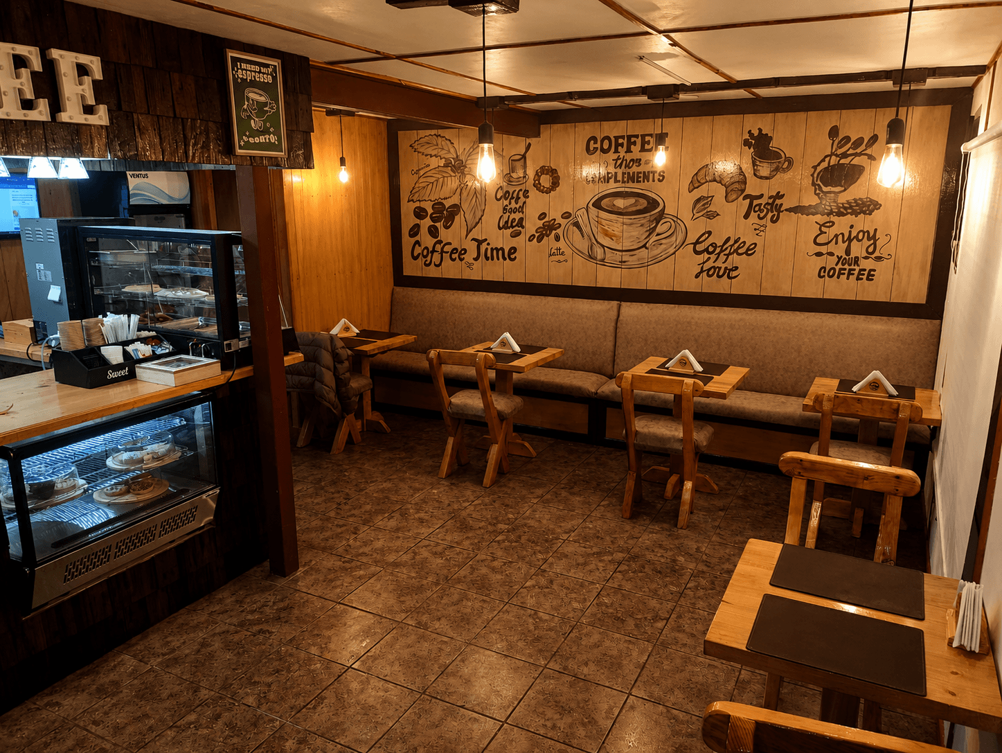 Salón de la cafetería Chaitén con mesas de madera y mural de café en la pared